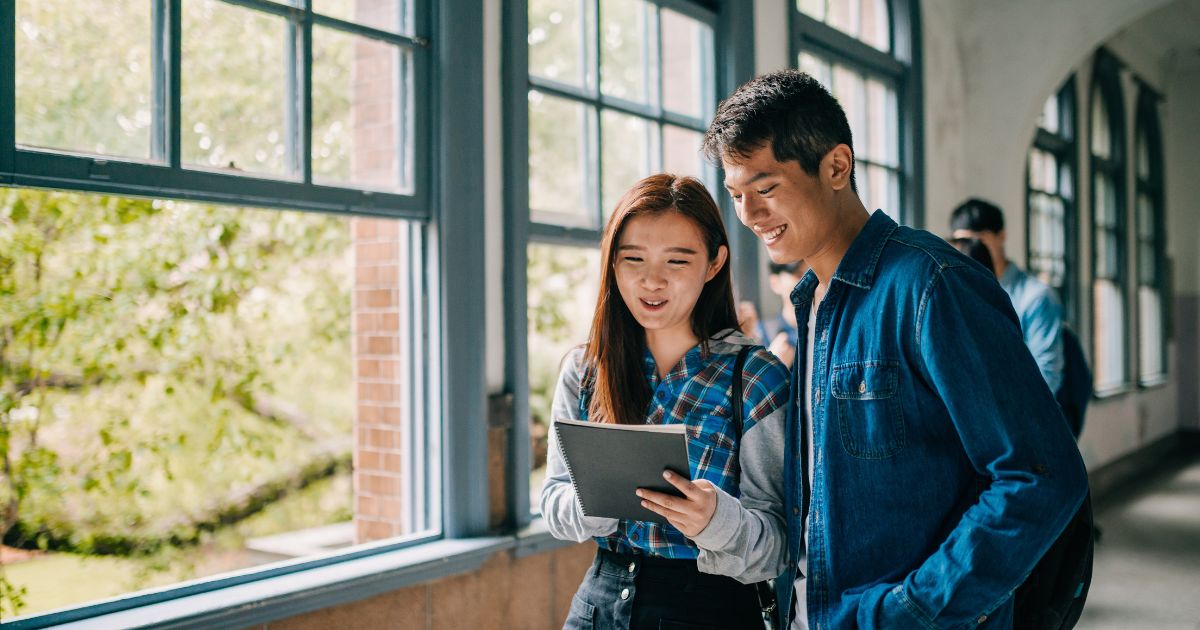 A girl and boy looking at a paper in the school hallway